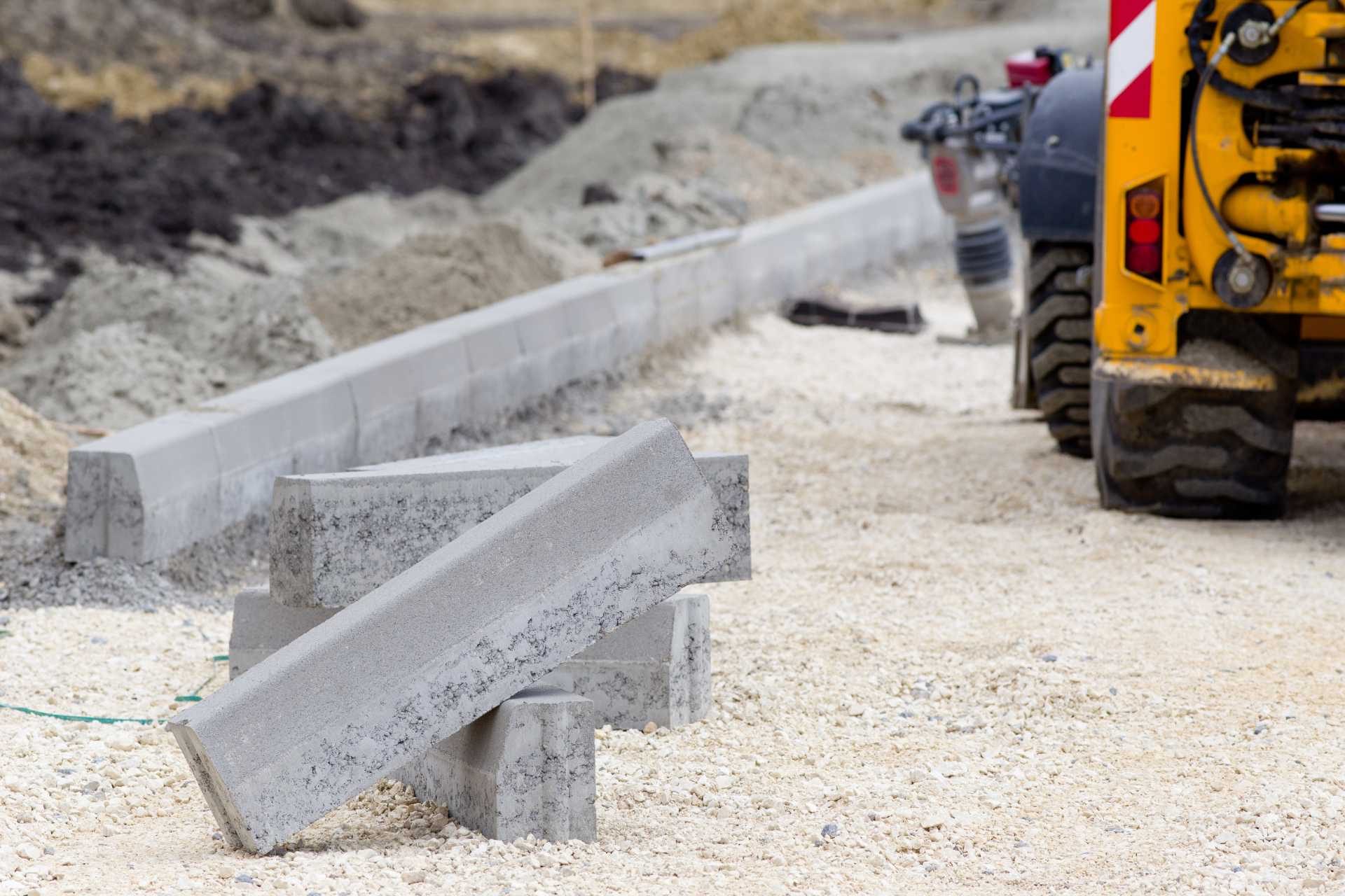 Concrete curbs and construction equipment at a roadwork site
